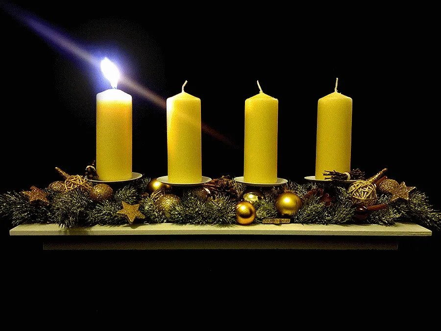 Vier gele kaarsen op een decoratieve kerstondergrond met sterren en ballen.