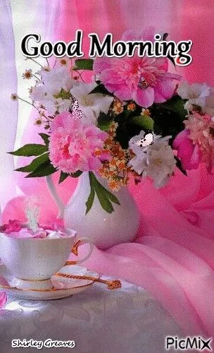 Vaasje met bloesems en een kopje thee op een zachte roze achtergrond.