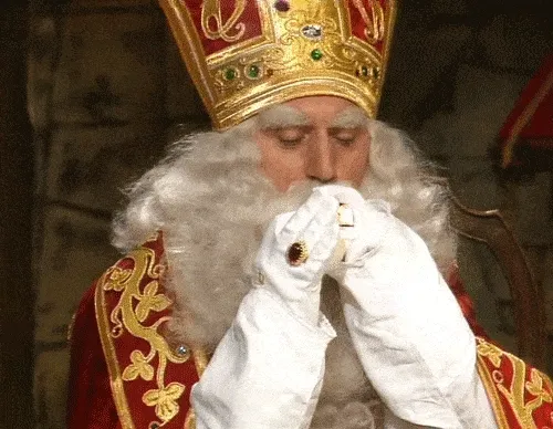 Een man in een koninklijk kostuum met een grote kroon en witte baard.