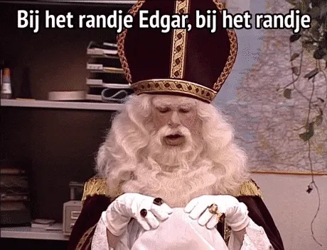 Een man in een koninklijk kostuum leest een tekst in een kantooromgeving.